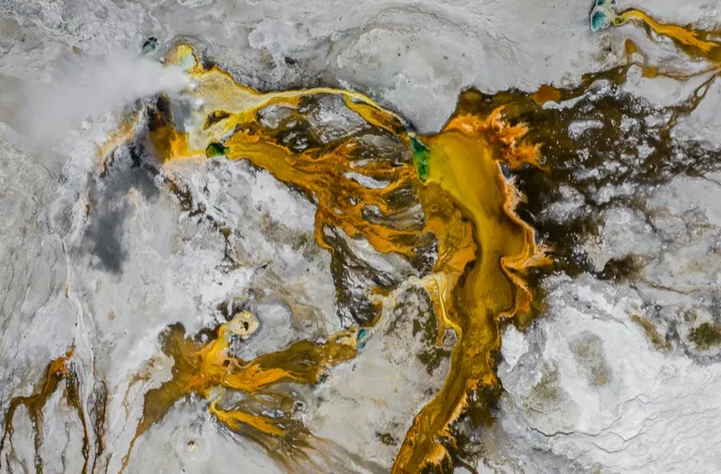 Aerial view of ochre mineral deposits threading across pale terrain